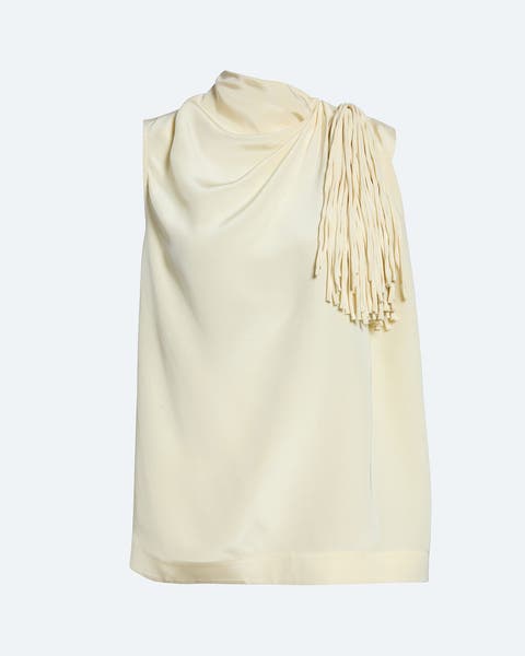 Sleeveless pale yellow top with a draped, cowl-like neckline gathered on one shoulder, featuring a cluster of matching fringe tassels at the shoulder detail