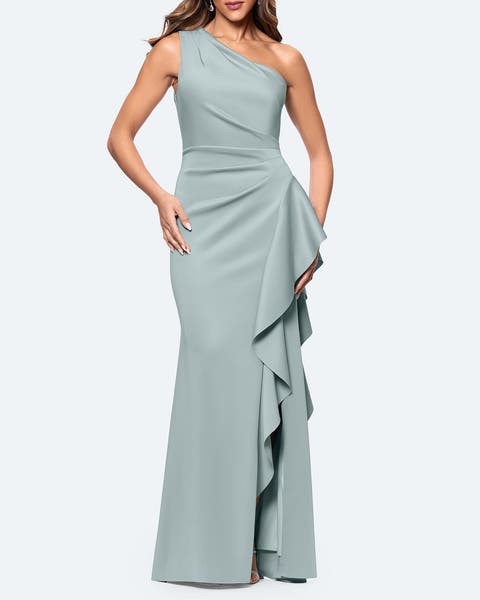 A woman wearing an seafoam green one shoulder with side ruffle gown.