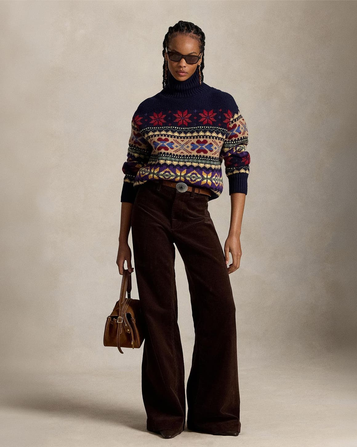 A woman wearing a fair isle sweater and brown corduroy pants.