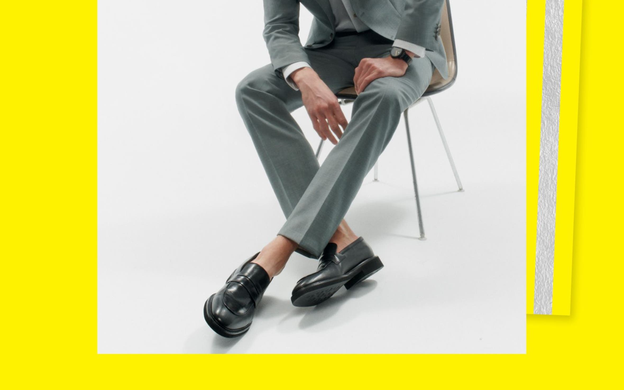 A man in a grey suit and dark leather loafers.
