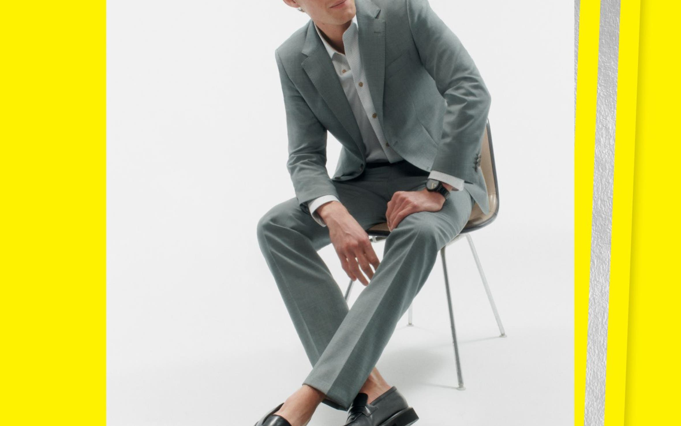 Man sitting in chair wearing a suit and loafers.