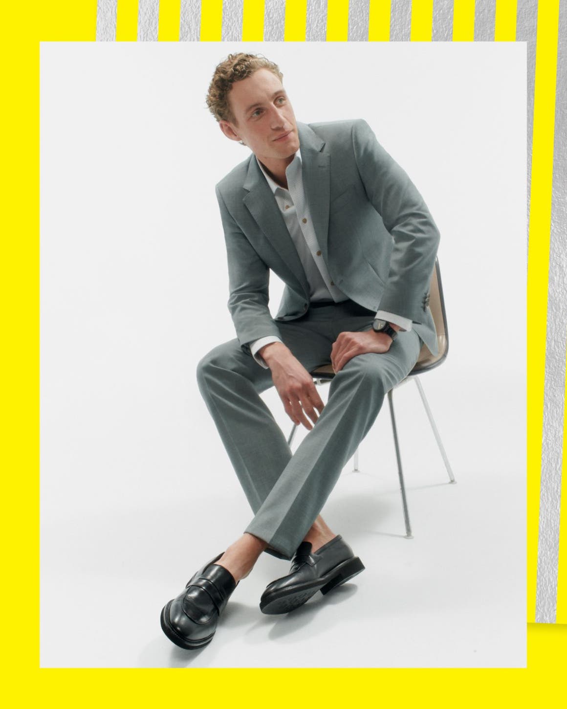 Man sitting in chair wearing a suit and loafers.