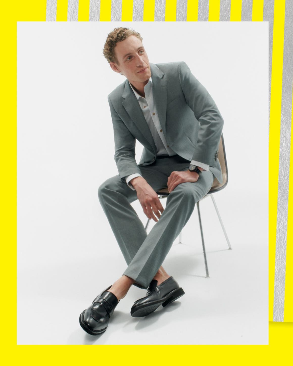 A man in a grey suit and dark leather loafers.