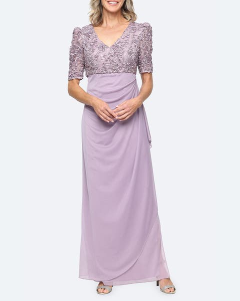 A woman in a three-quarter sleeved purple embroidered dress and silver heels. 