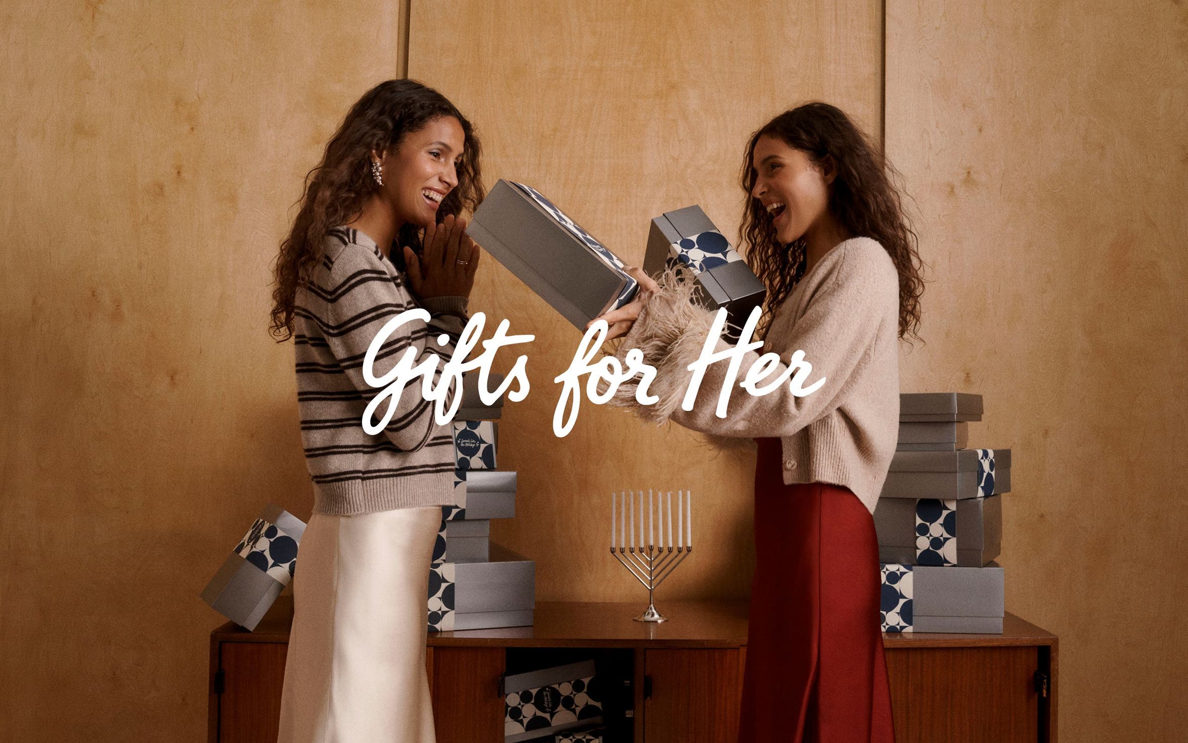 Gifts for her under $100; two women exchanging gifts. 