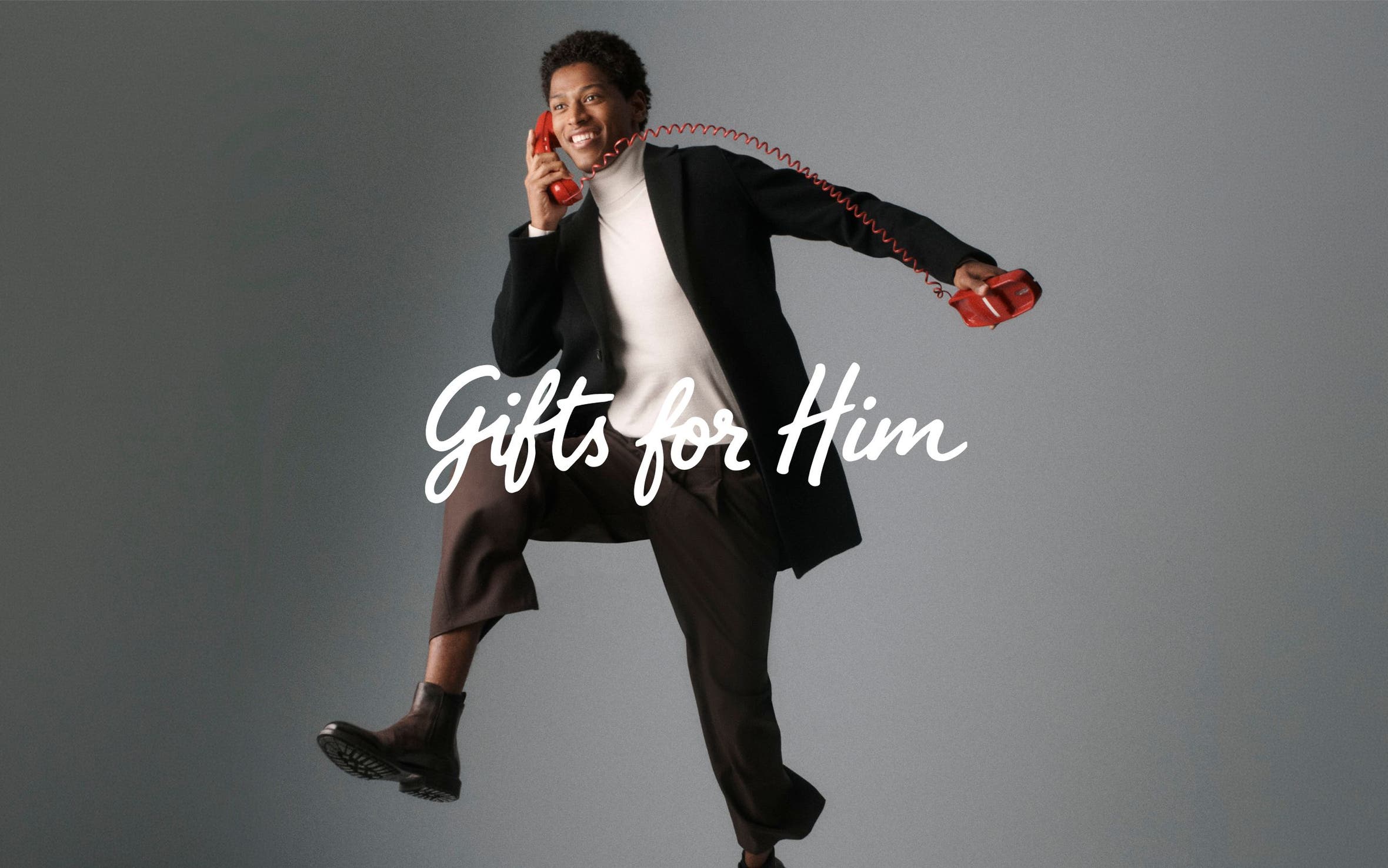 Gifts for him. A man in a turtleneck, blazer and pants on a corded telephone.