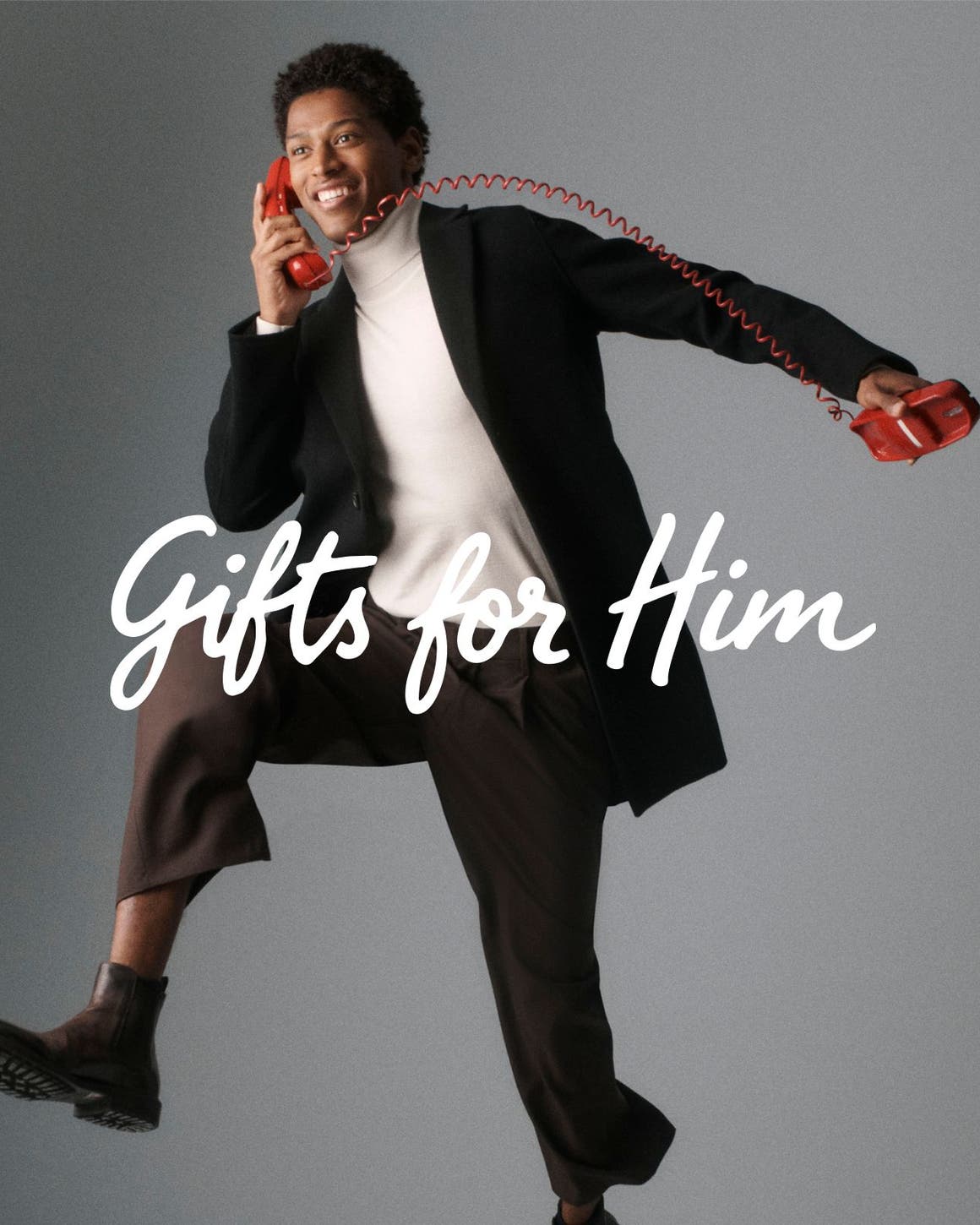 Gifts for him. A man in a turtleneck, blazer and pants on a corded telephone.