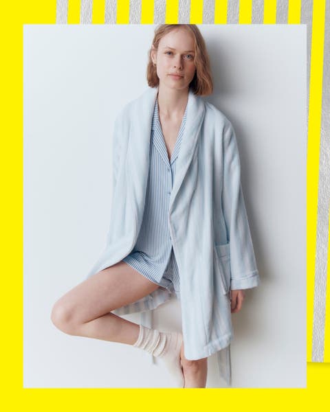 A woman wearing a blue stripe pajama set and light blue short robe.