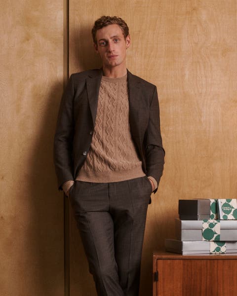 A man wearing a sweater, blazer and pants.