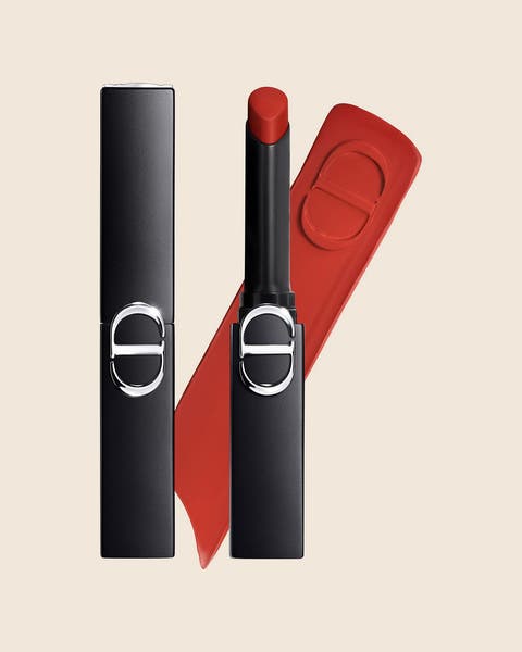 A DIOR lipstick in a slim black case, shown open with a tomato red bullet and a matching swatch.