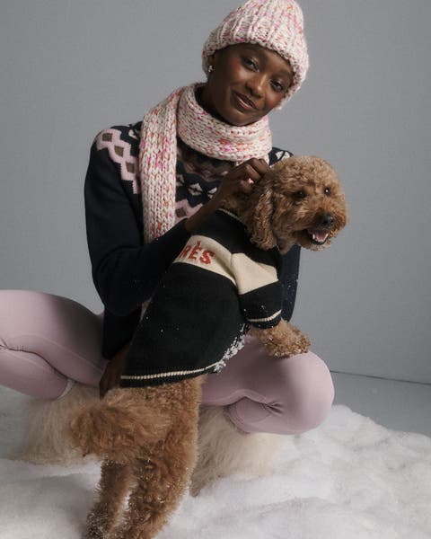 A woman with a dog in a sweater.