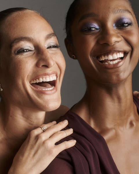 Two laughing women wearing sparkling eyeshadow.