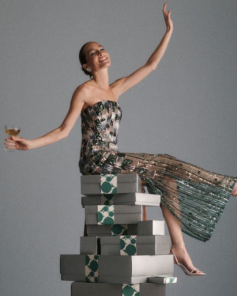 A woman in a gown sitting on a stack of Nordstrom gift boxes.