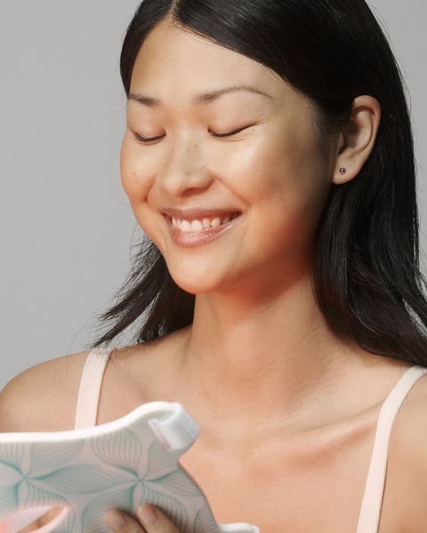 A woman holding a red light mask. 