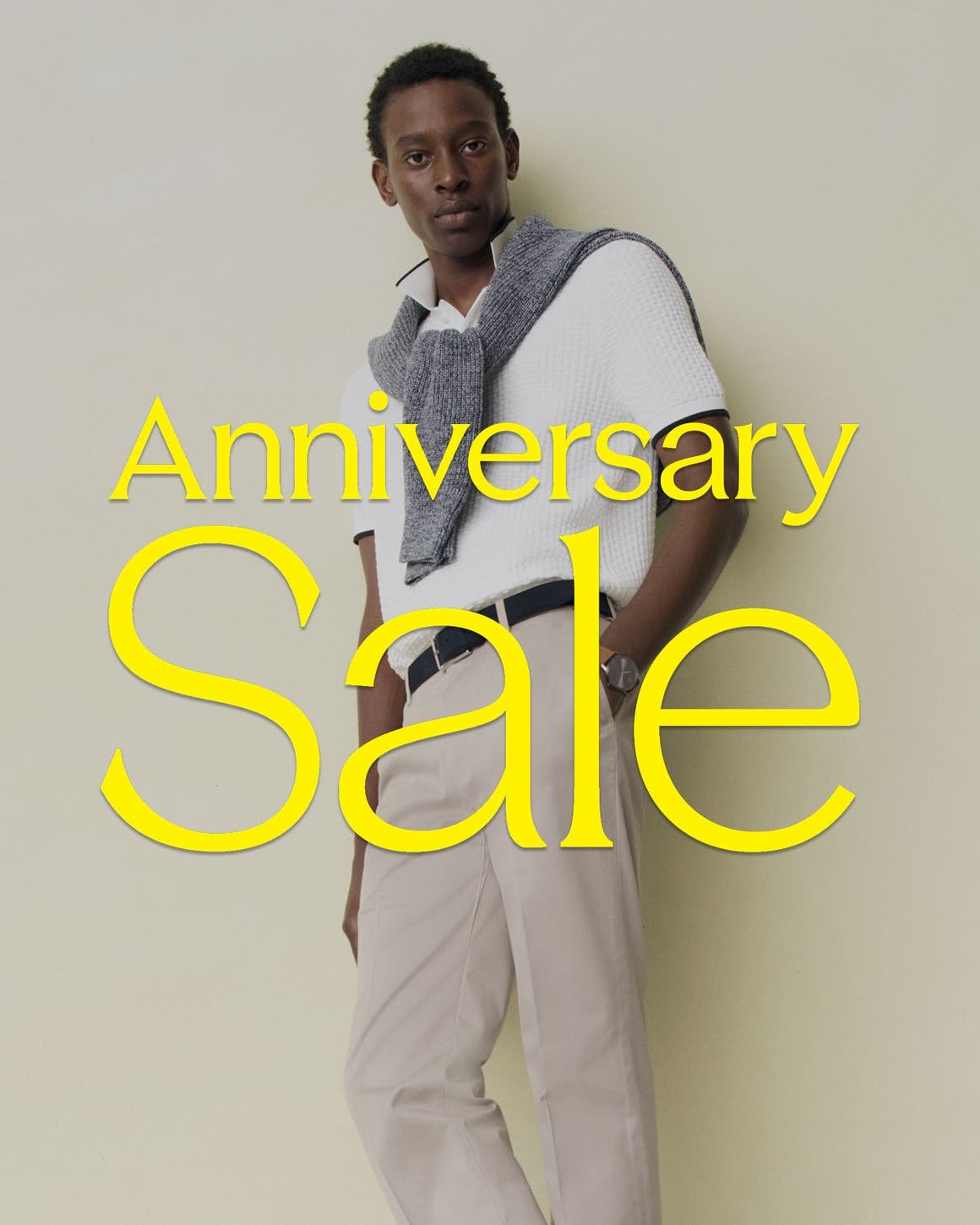 Anniversary Sale: a man in a white polo, tan pants and sweater around his shoulders.
