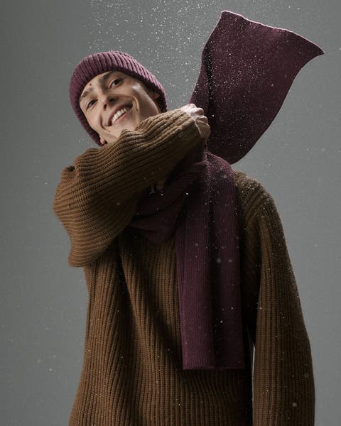 A man wearing a sweater with a beanie and matching scarf.