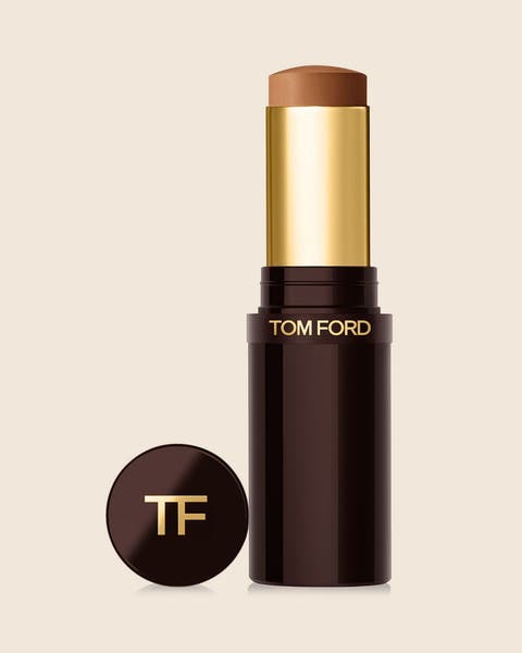 A TOM FORD complexion stick in a glossy dark brown tube with a gold TF logo on the cap.