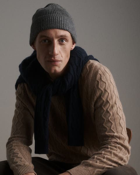 A man wearing a sweater, beanie and scarf.