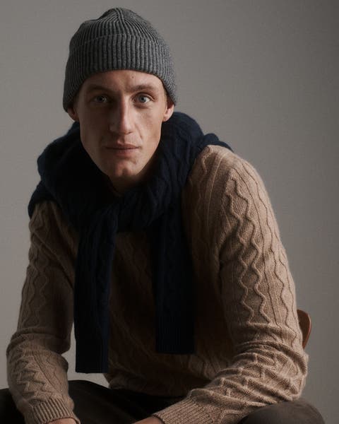 A man wearing a sweater, beanie and scarf.