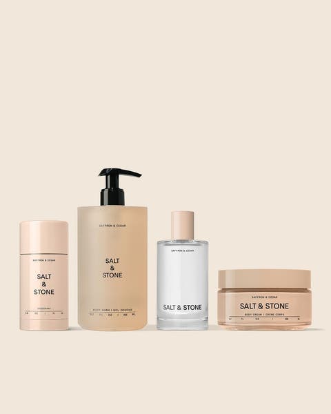 Four SALT & STONE body care products: a deodorant stick, pump bottle, fragrance and body cream.
