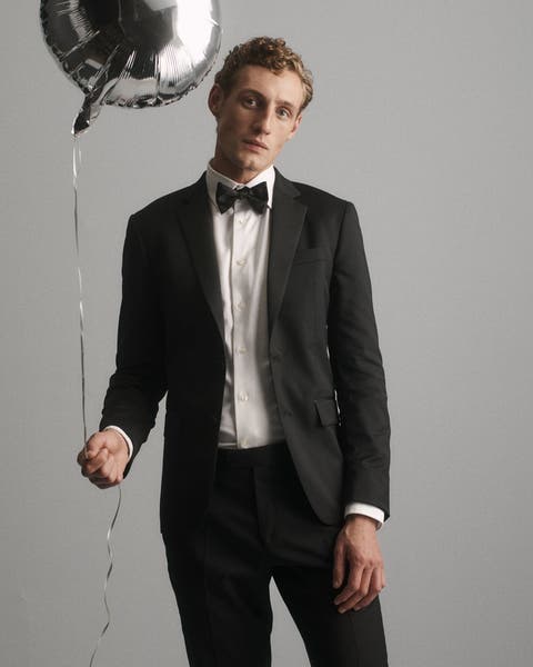 A man wearing a suit and holding a balloon.