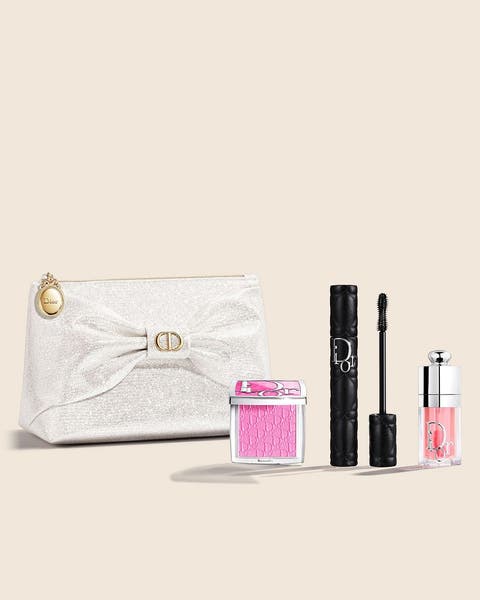 A DIOR beauty set with a cream bow pouch, pink blush, black mascara and a pink lip oil.