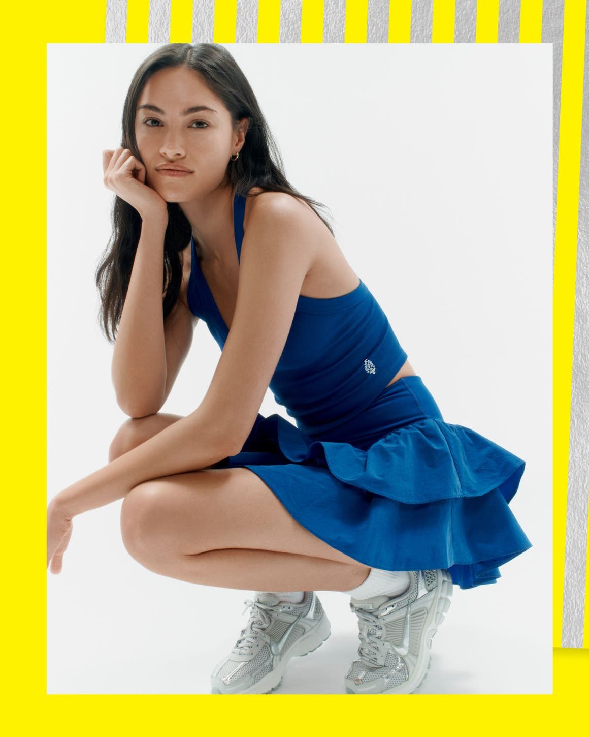 A woman wearing a blue tank and blue ruffle active skirt. 