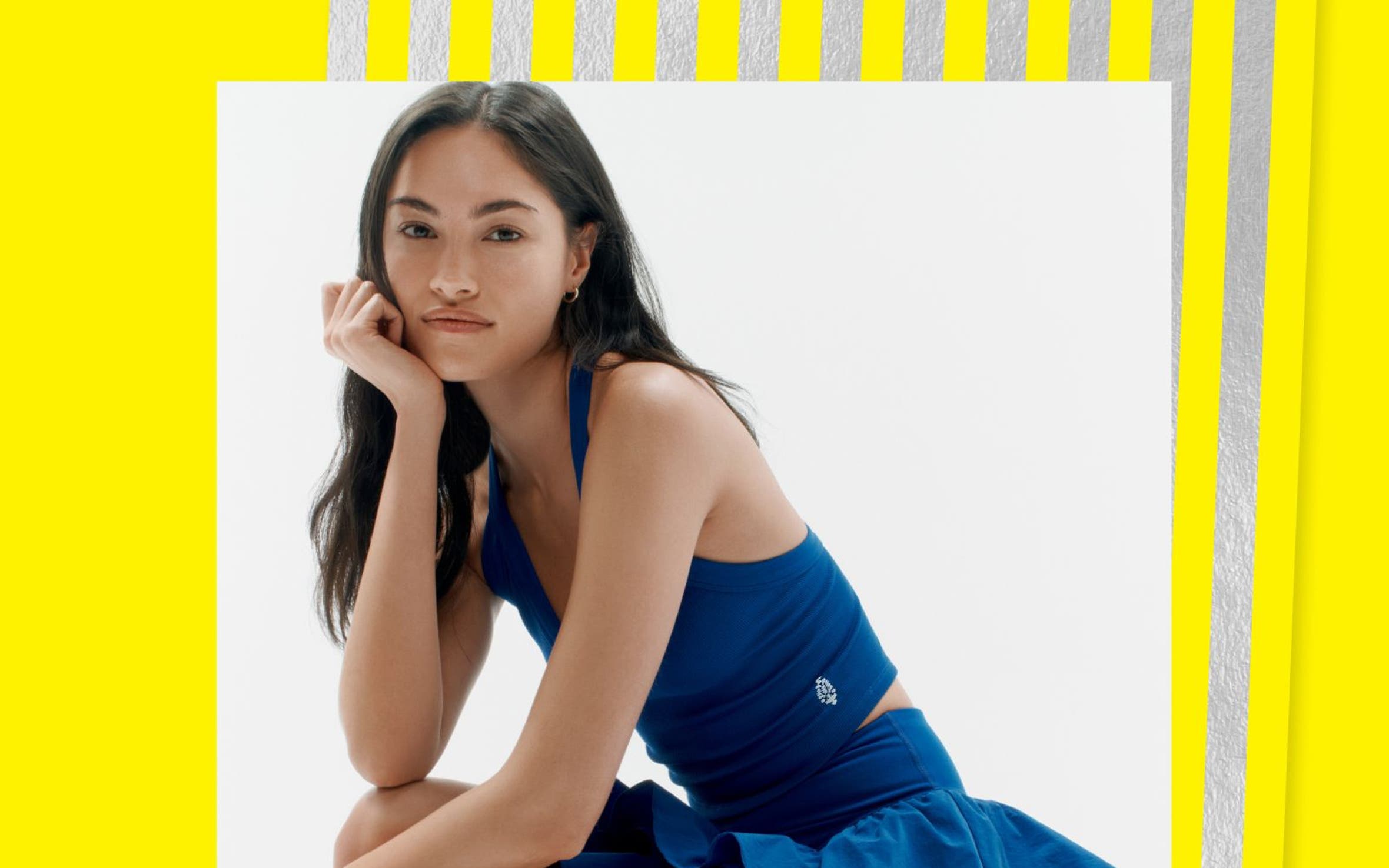 A woman wearing a blue tank and blue ruffle active skirt. 