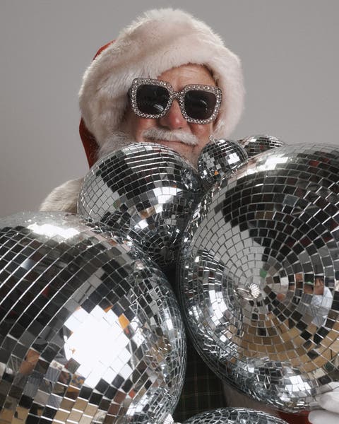 Santa Claus wearing sparkly sunglasses and holding disco balls.