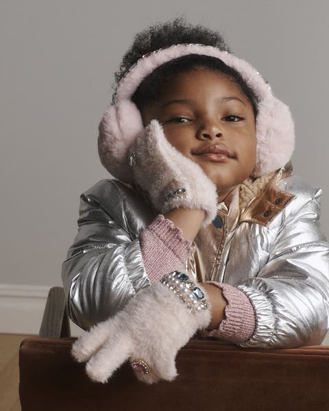 A girl wearing earmuffs, gloves and a silver jacket.