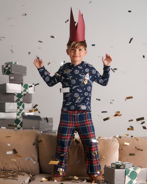 A boy wearing pajamas and a crown with stacks of Nordstrom gift boxes.
