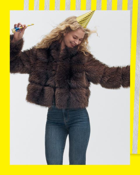 A woman in dark straight-leg jeans and a brown cropped faux fur jacket.