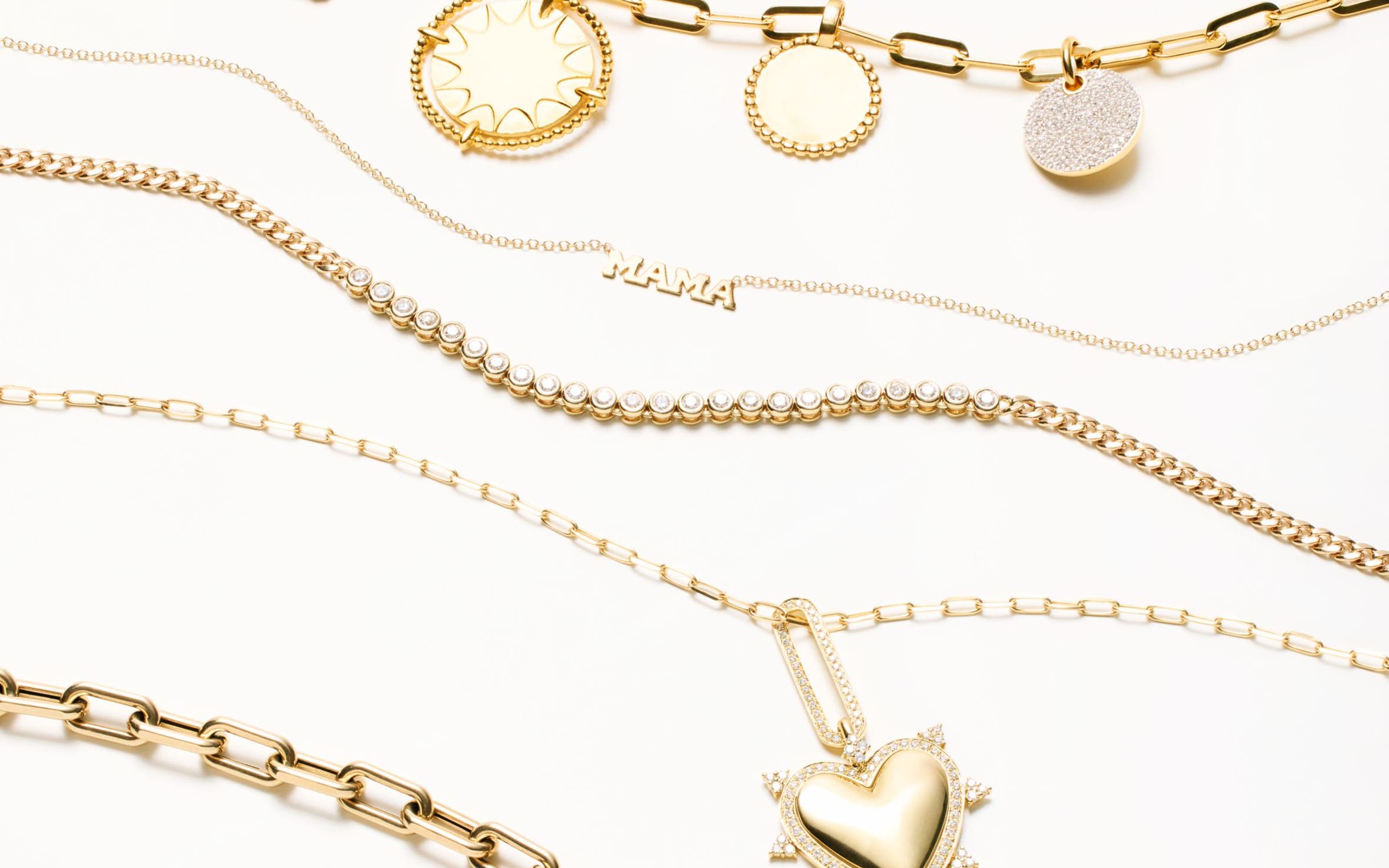 Gold-colored necklaces with gems and charms, including a heart-shaped charm and a "Mama" pendant. 