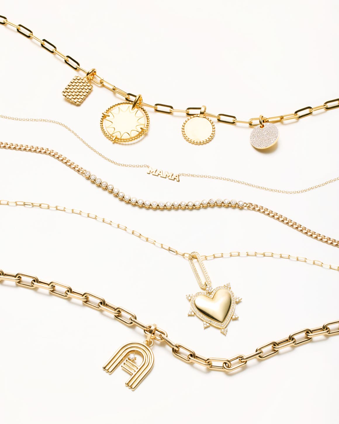Gold-colored necklaces with gems and charms, including a heart-shaped charm and a "Mama" pendant. 