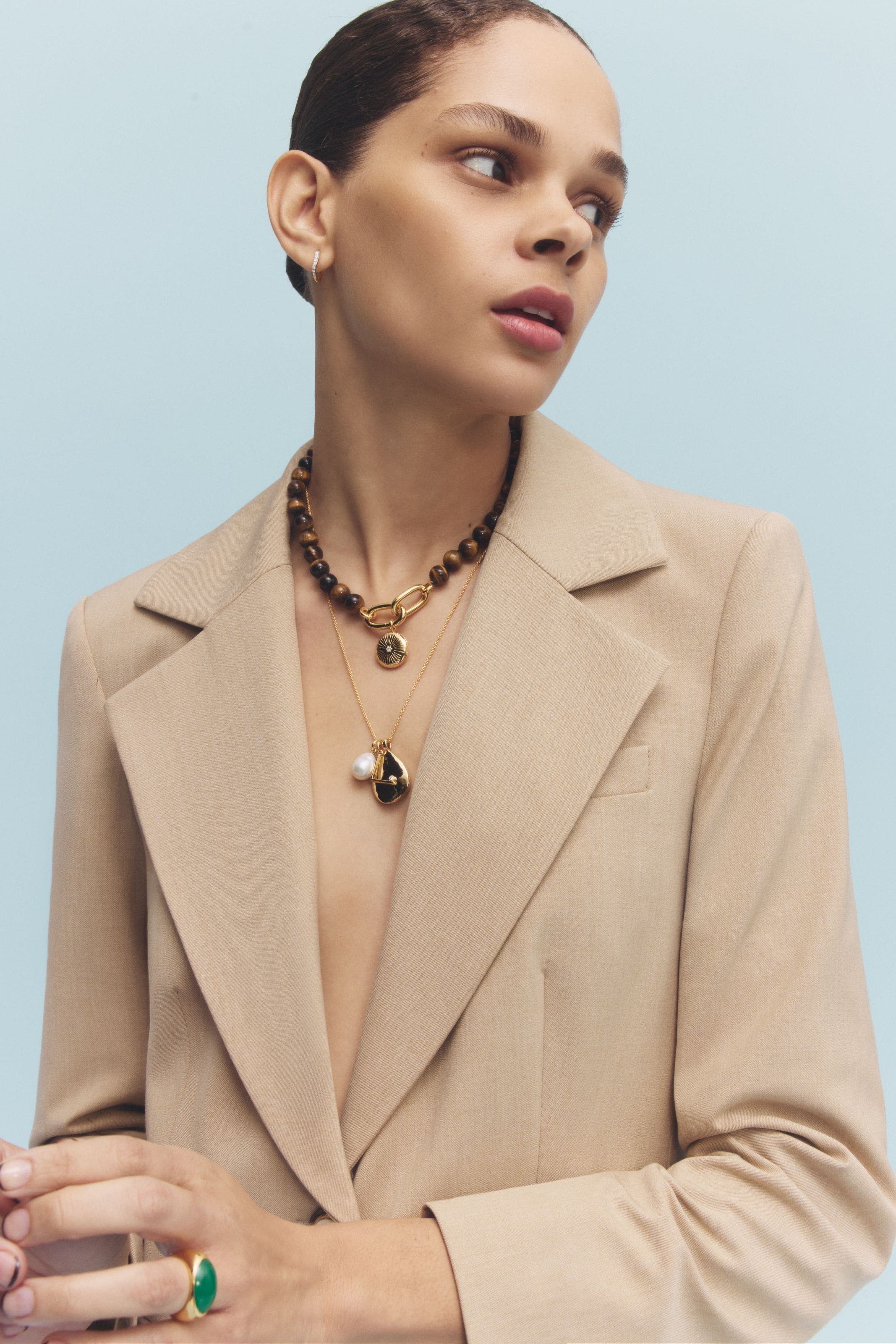 A woman wearing a beaded locket and a chain necklace.