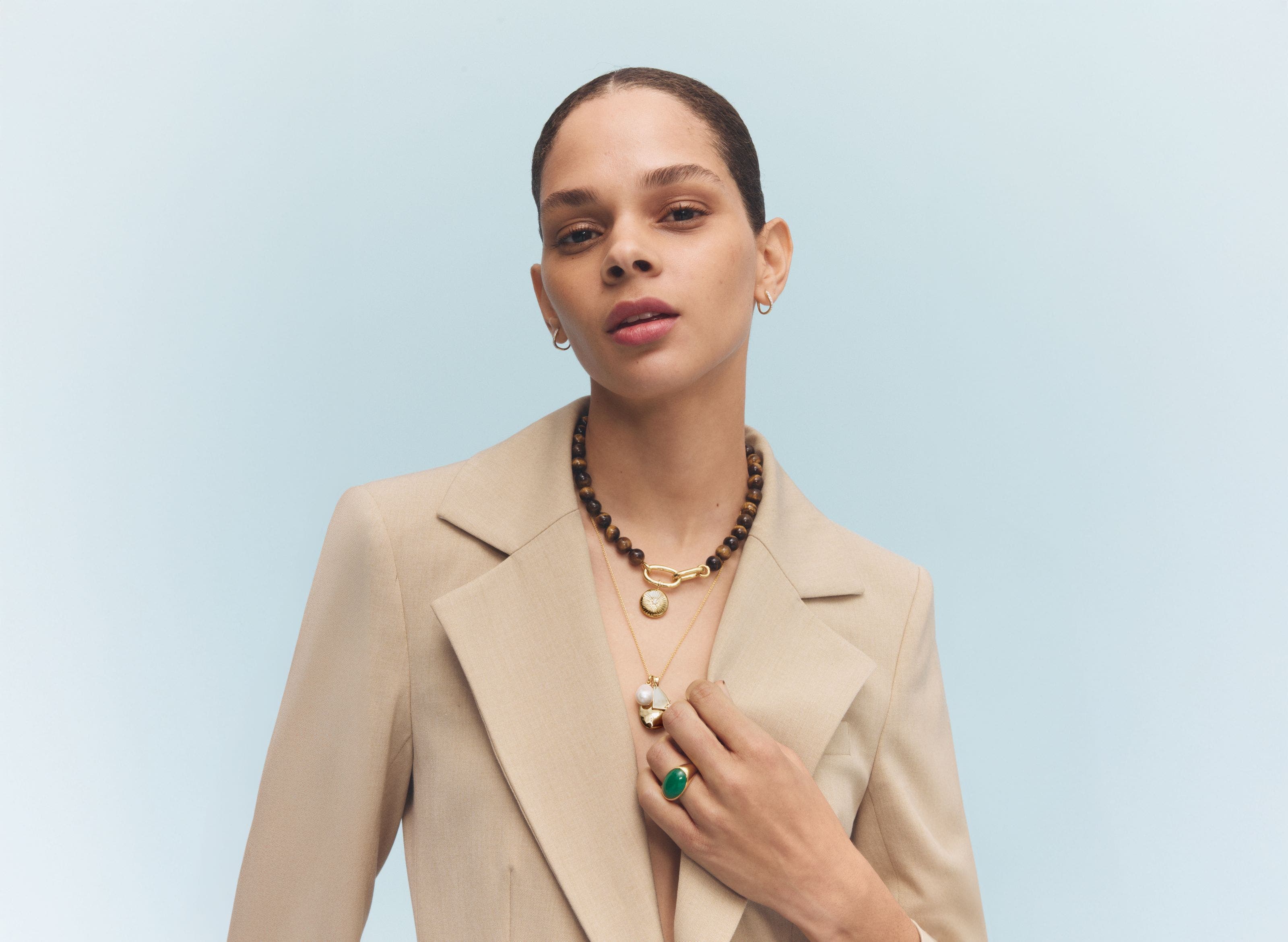 A woman wearing earrings, necklaces and a ring.
