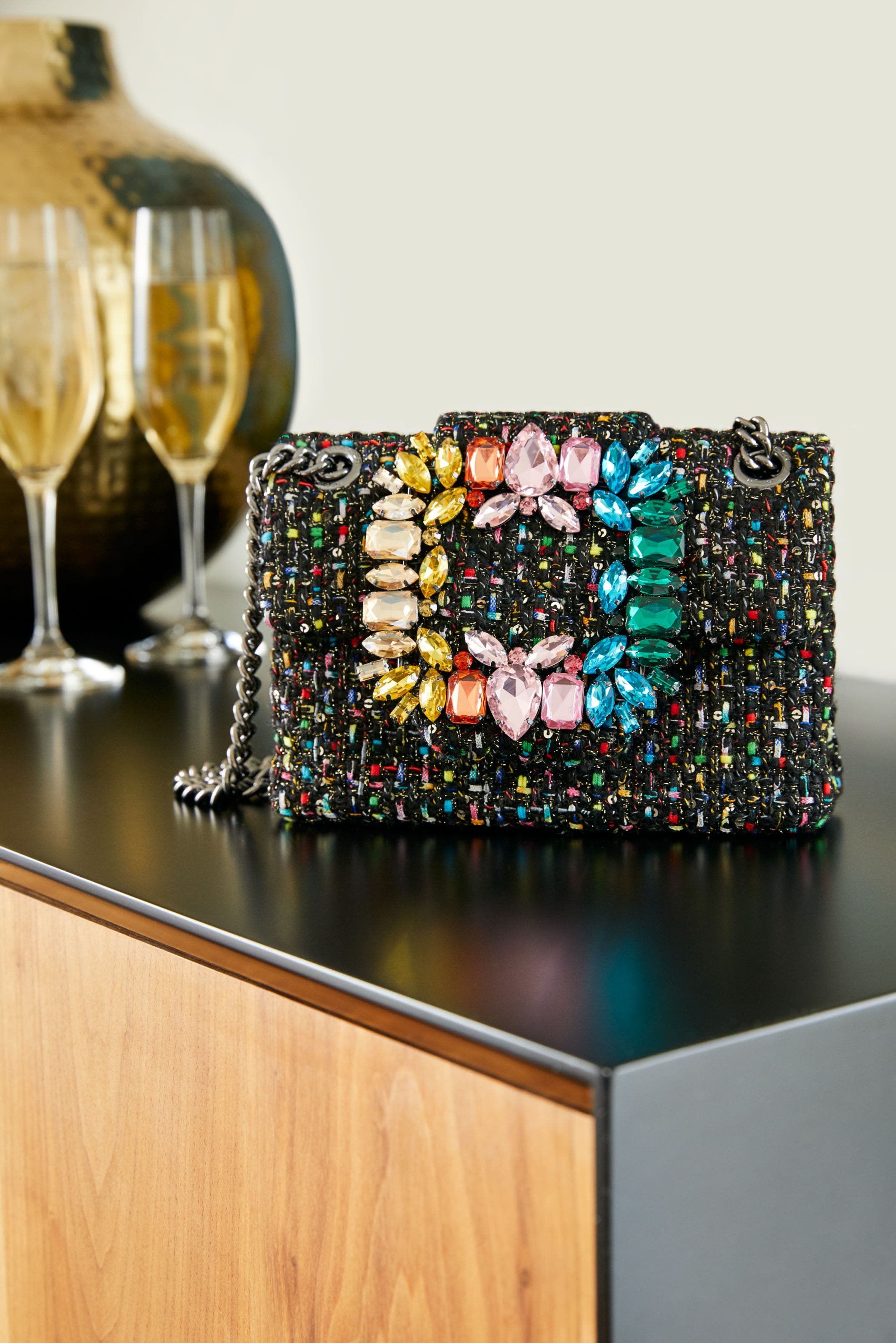 Product shot of black clutch with colorful jewels.