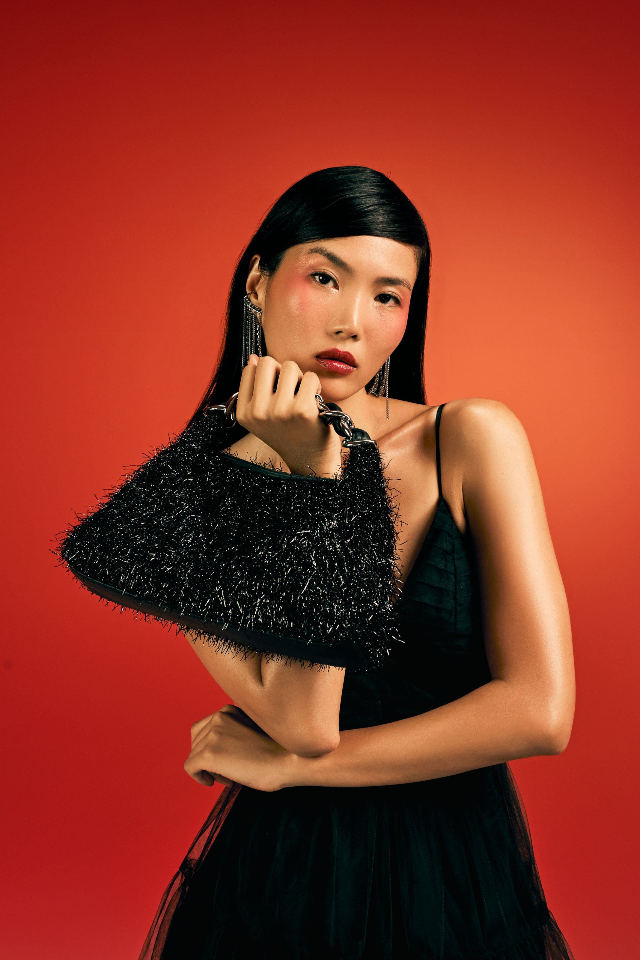 Model in black dress with black handbag.