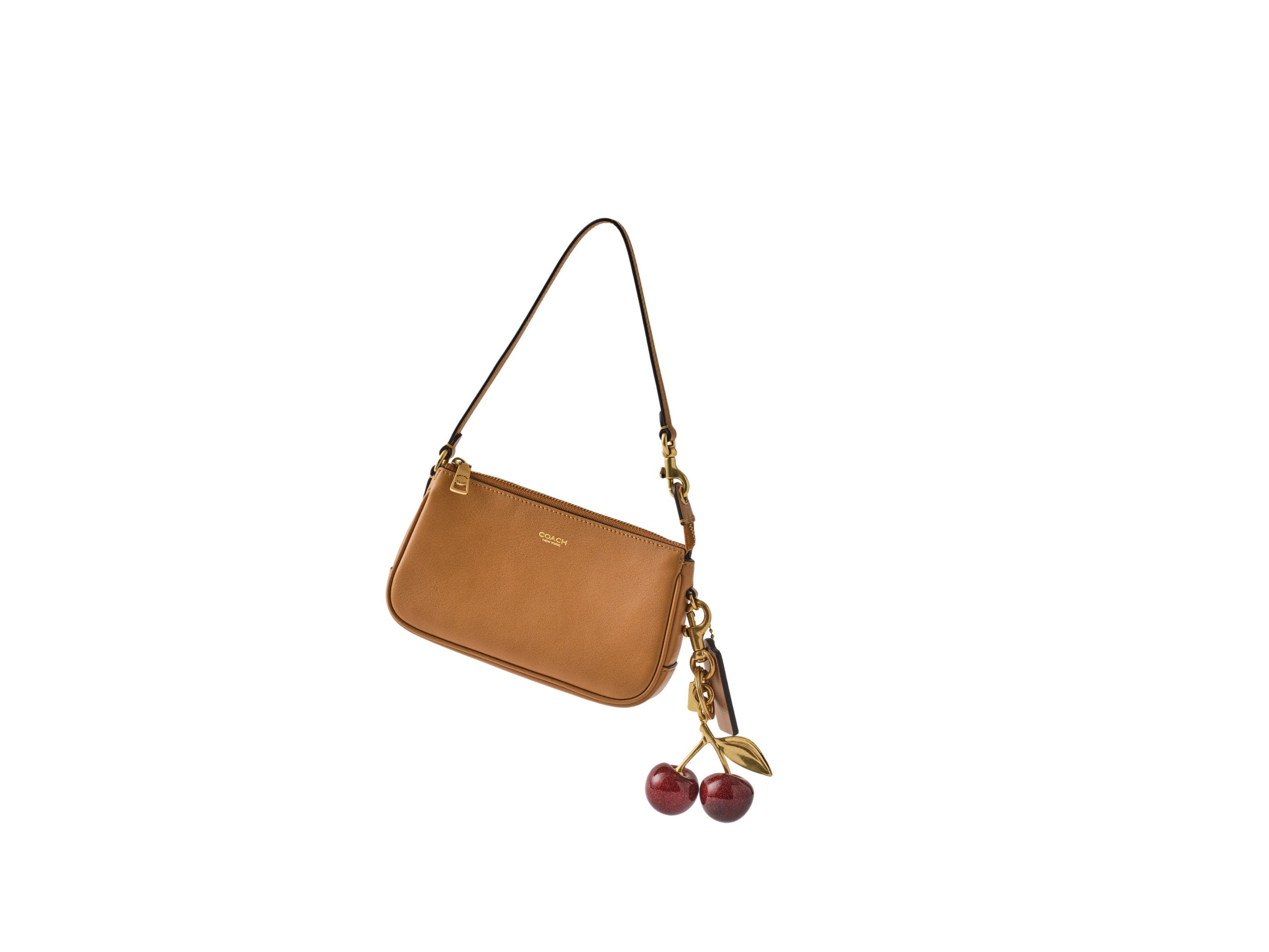 A Coach handbag with a cherry bag charm. 