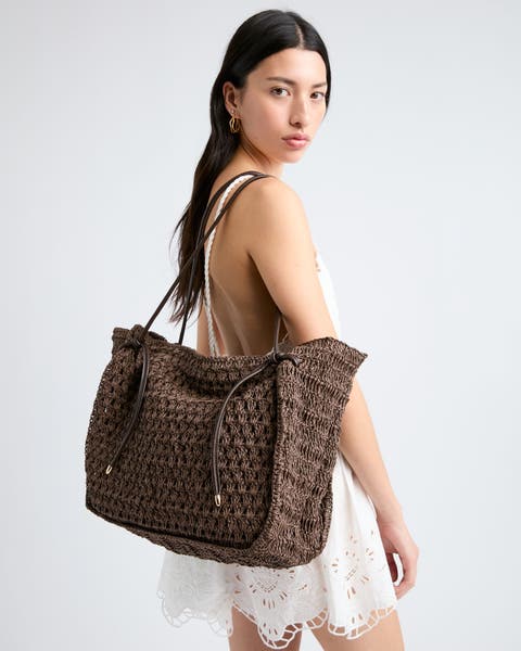 Woman wearing a large woven tote bag.