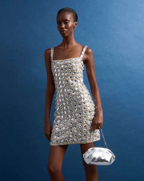 A woman in a silver embellished mini dress with a matching bag.