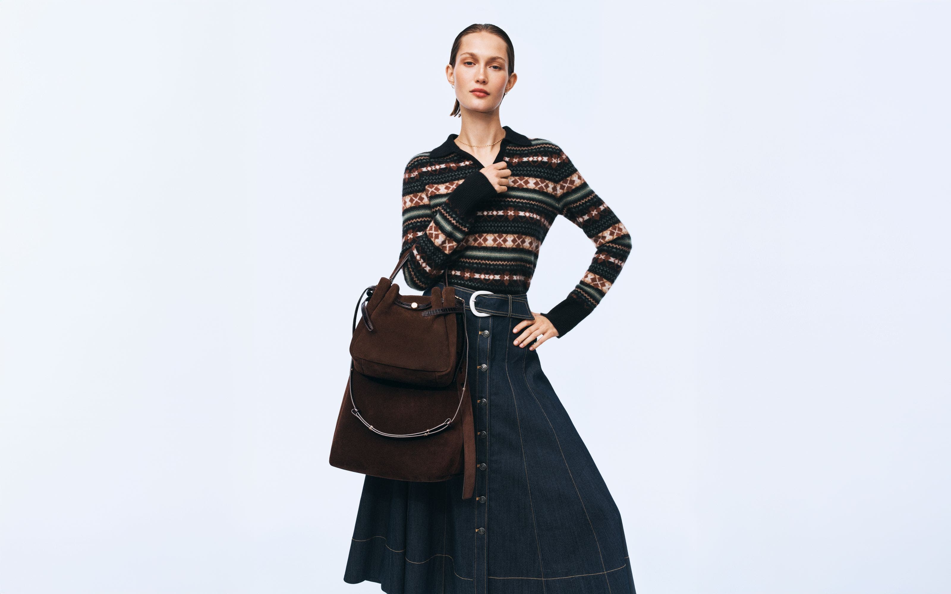 A woman wearing a fair isle polo sweater and denim skirt.