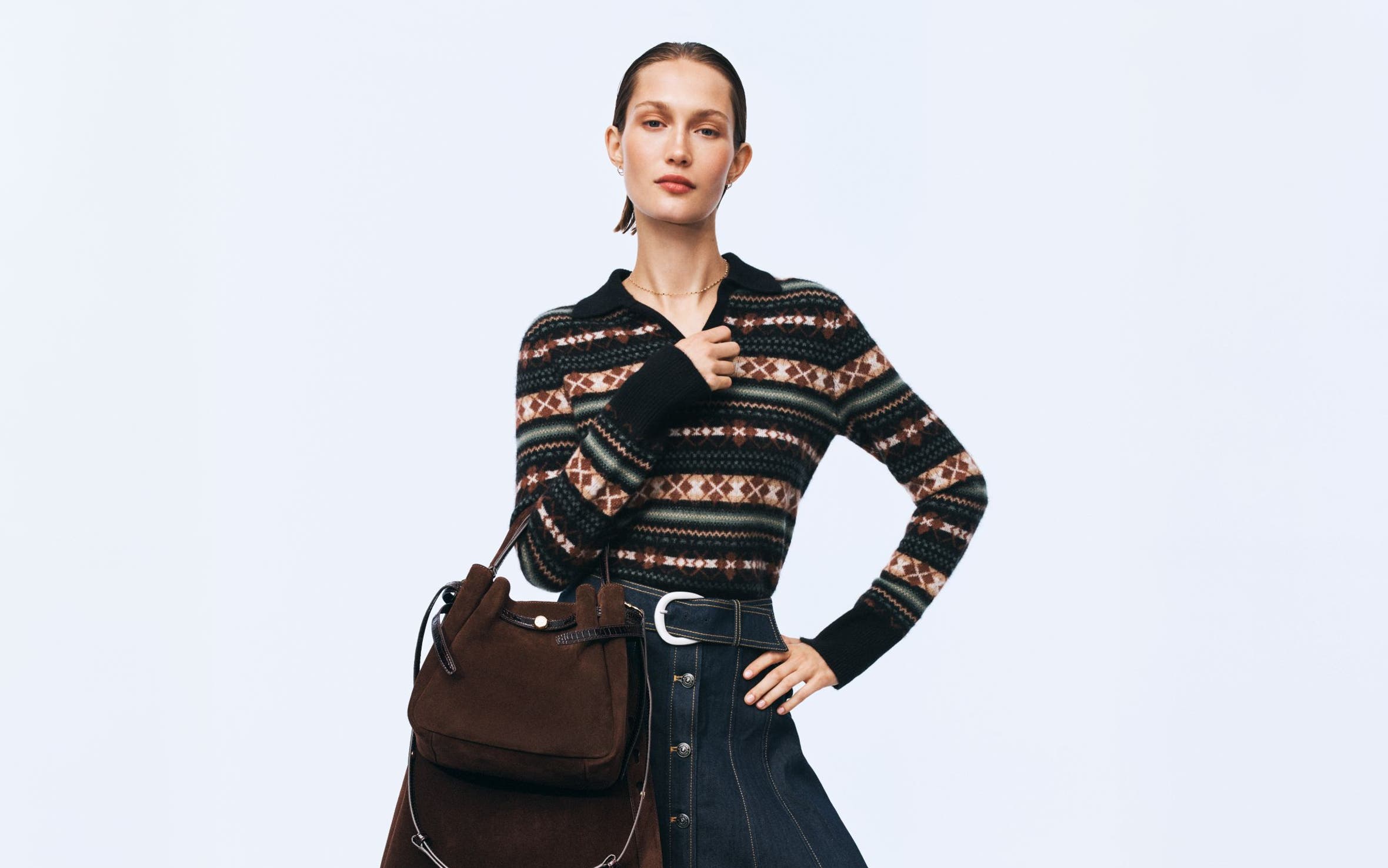 A woman wearing a fair isle polo sweater and denim skirt.