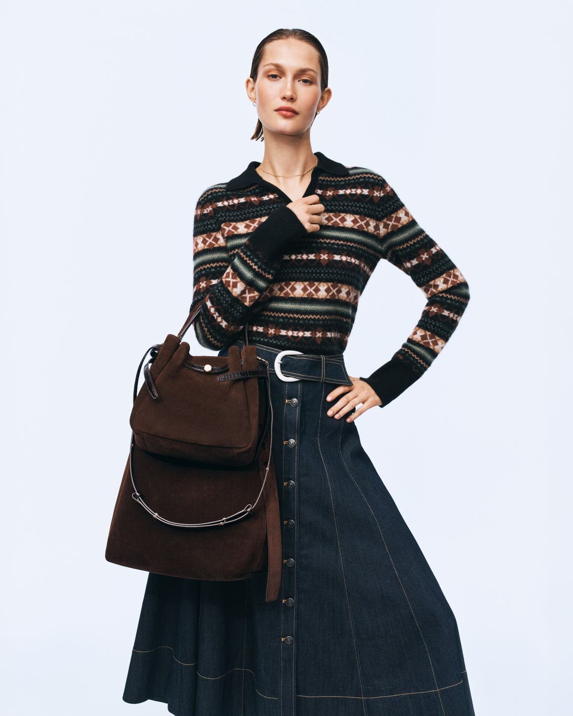 A woman wearing a fair isle polo sweater and denim skirt.