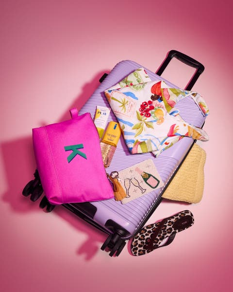 Lavender suitcase with pink pouch, sunscreen, tropical top, straw hat, and leopard flip-flop.