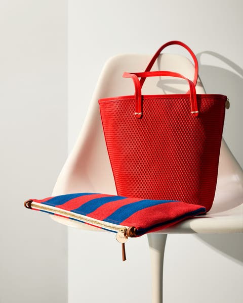 A red tote bag and striped zip case. 