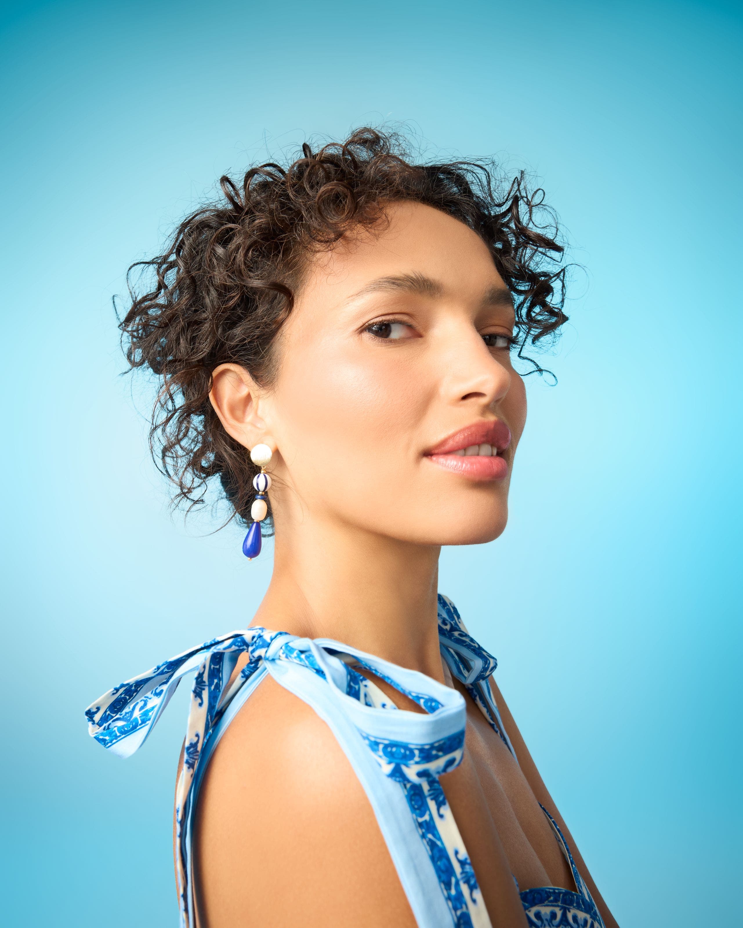 A woman wearing linear beaded drop earrings.