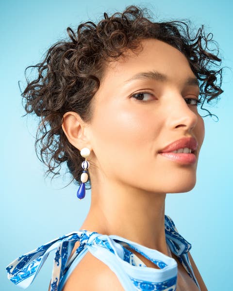 A woman wearing linear beaded drop earrings.