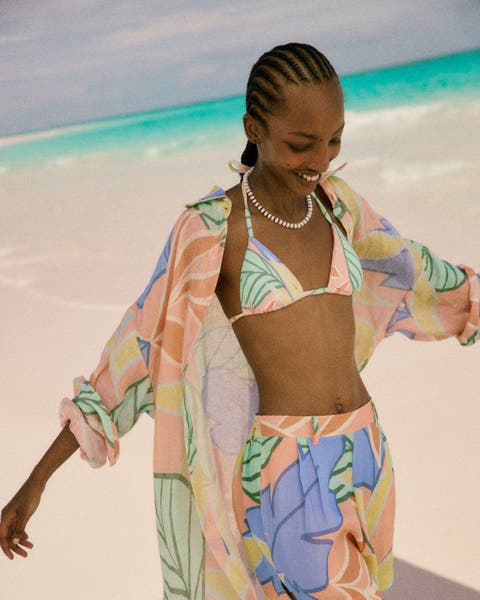 Woman wearing a tropical-pattern swimsuit and cover-up.
