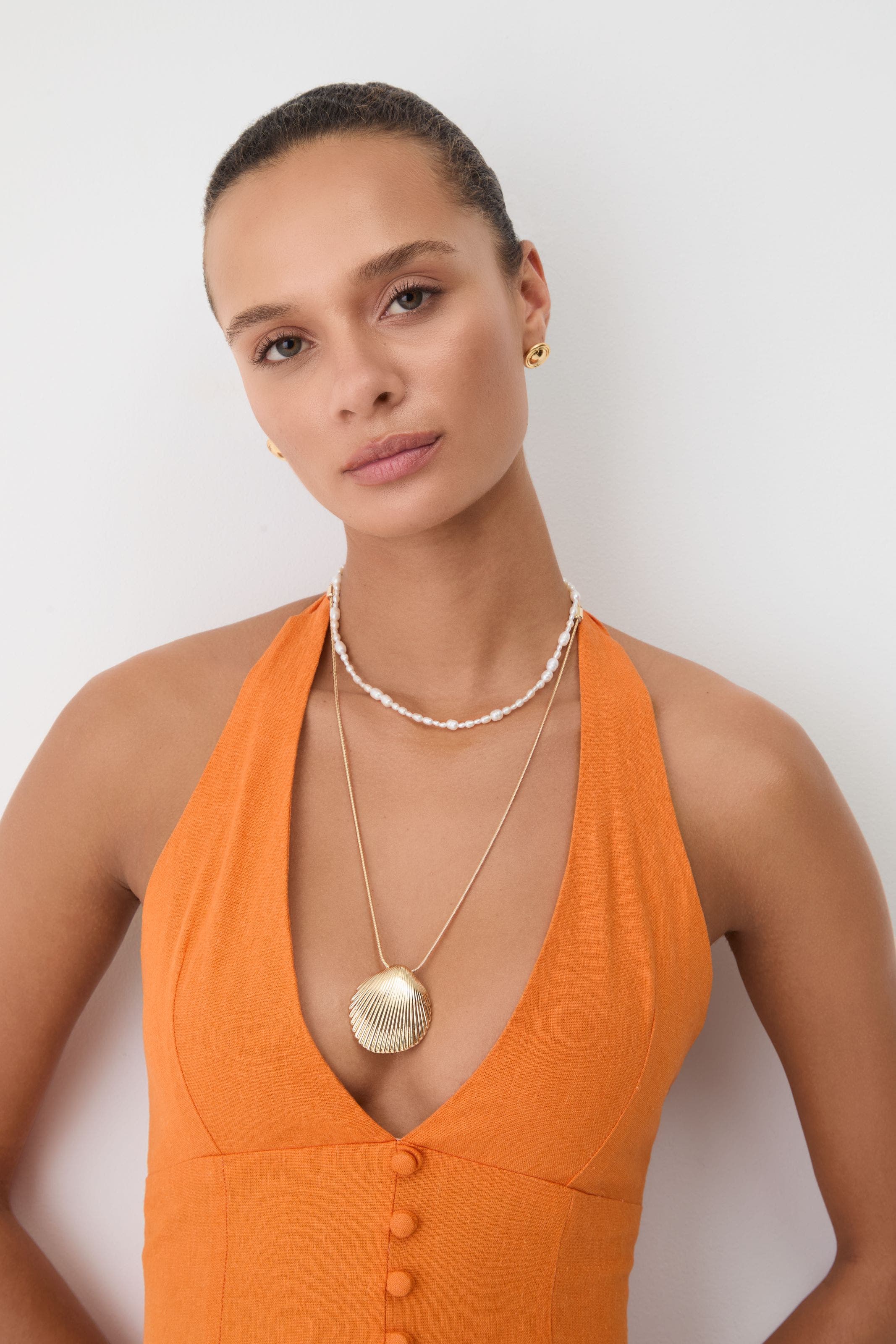 A woman wearing a beaded necklace and shell pendant.